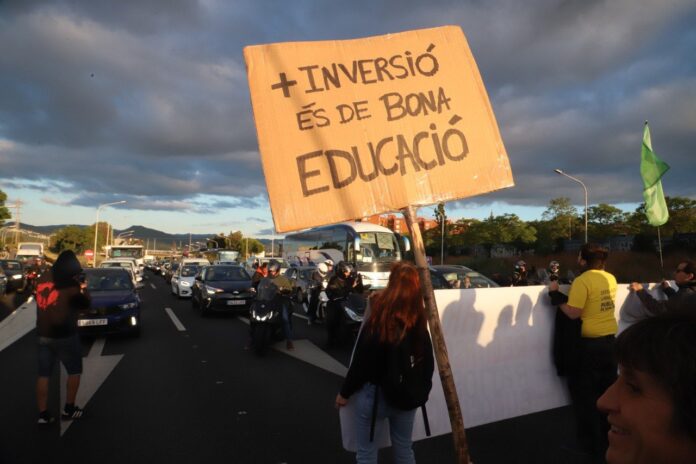 Docentes protestando y cortando la B-23 en Sant Joan Despí durante la huelga educativa en Cataluña con pancartas reclamando más inversión en educación.