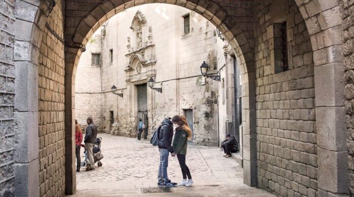 Personas paseando en una calle del centro histórico de Barcelona con edificios patrimoniales