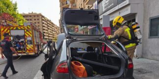 Bomberos inspeccionan el coche que explotó en el centro de Lleida y dejó cinco personas heridas.