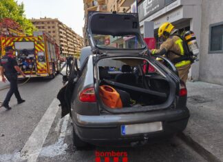 Bomberos inspeccionan el coche que explotó en el centro de Lleida y dejó cinco personas heridas.