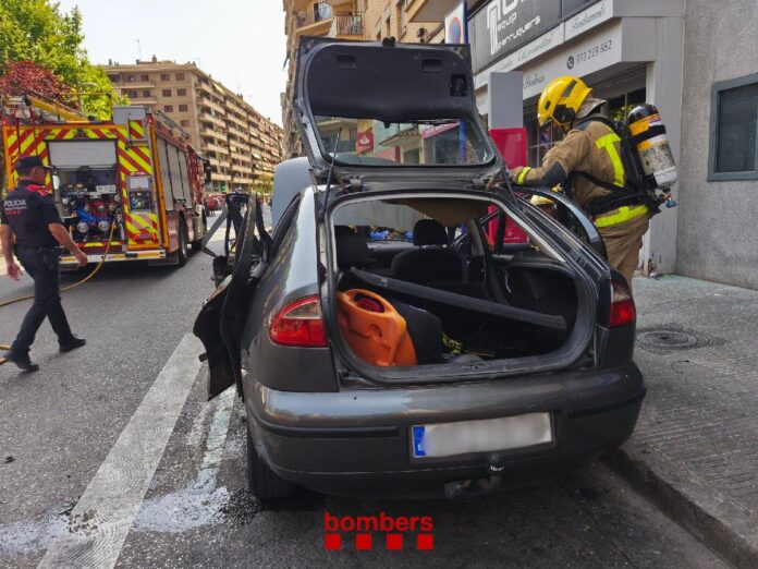 Bomberos inspeccionan el coche que explotó en el centro de Lleida y dejó cinco personas heridas.
