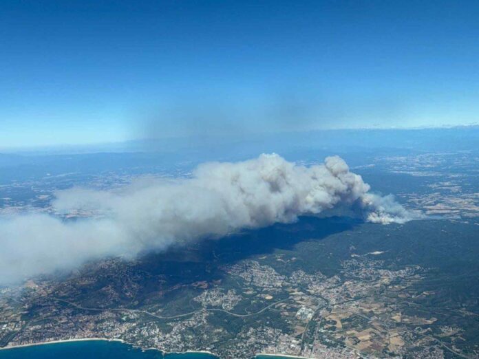 Vista aérea de la gran columna de humo provocada por el incendio forestal de Les Gavarres, en el Baix Empordà, junto a varias zonas urbanizadas.