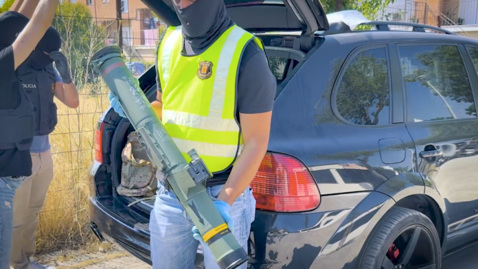Agente de la Policía Nacional sostiene el lanzacohetes intervenido durante la operación contra una red de tráfico de armas en Cataluña.