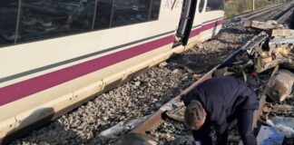 Un hombre examina los restos esparcidos sobre las vías junto a uno de los trenes implicados en el accidente ferroviario ocurrido este miércoles en Toledo.