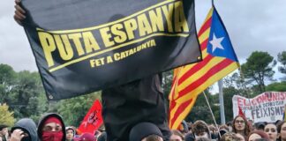 Manifestantes encapuchados con una estelada y pancartas independentistas y comunistas durante las protestas contra Vito Quiles en la UAB.