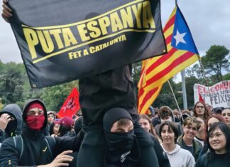 Manifestantes encapuchados con una estelada y pancartas independentistas y comunistas durante las protestas contra Vito Quiles en la UAB.